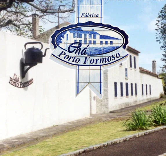 Chá Porto Formoso factory building with white walls, black kettle wall lamp, and green plants outside