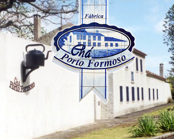 Chá Porto Formoso factory building with white walls, black kettle wall lamp, and green plants outside