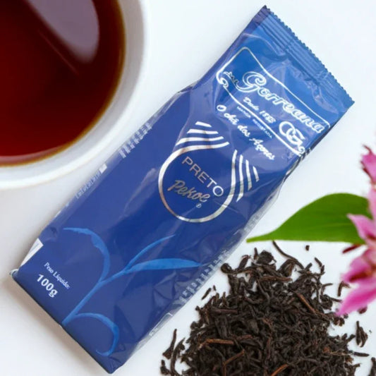 Package of 100g Gorreana Preto Pekoe organic black tea with loose leaves, cup of tea, and pink flower