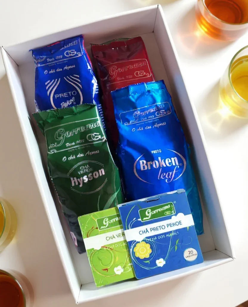 Gift Box - 6 Pack Organic Premium Tea Gorreana Azores (4x100g Loose Leaf + 2x10 Tea Bags) - Gift box with assorted Garreaucha tea packages including Hysson green tea and Broken Leaf black tea with tea cups on white table