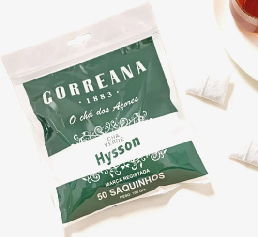Pack of Correana Hysson green tea with 50 sachets displayed next to two tea bags and a cup of tea