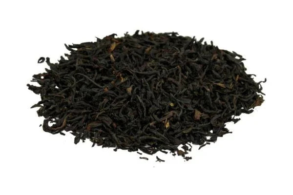 Loose dried black tea leaves piled on a white background for brewing