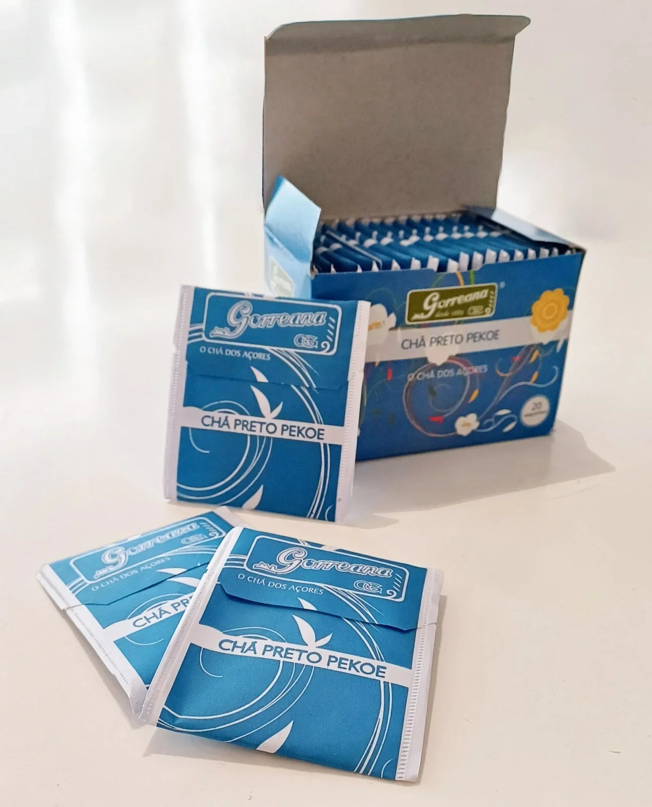 Blue Garreana Cha Preto Pekoe black tea sachets and open box on white surface